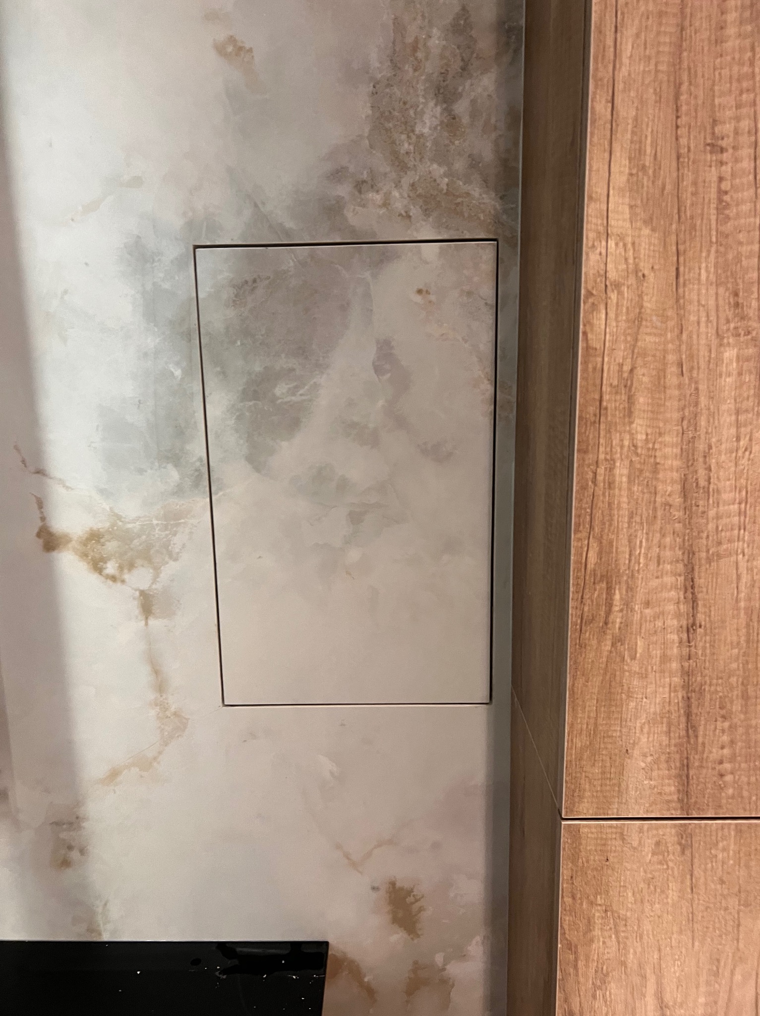 Ukryta rewizja w łazience w Bielawie. Płytki imitujące marmur, drewniane wykończenie szafki. Minimalistyczny design, precyzyjne wykonanie.