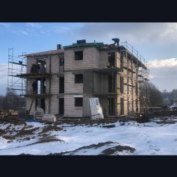 ELMAL - Budowa bloku mieszkalnego w Tychach, w trakcie prac murarskich. Widoczne rusztowania i pracownicy na dachu. Zimowy krajobraz z resztkami śniegu.