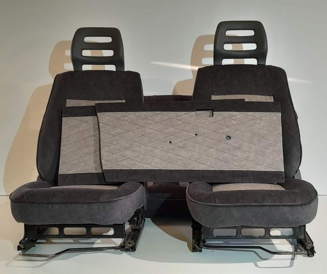 Odnowione, ciemnoszare fotele samochodowe z jasnoszarymi wstawkami i wzorem w romby na panelu drzwiowym, widoczne metalowe ramy foteli.
