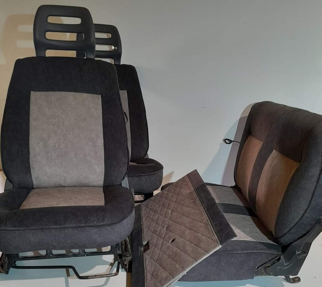 Komplet odnowionych, szaro-grafitowych foteli samochodowych z zagłówkami i panelem drzwiowym z pikowaną tapicerką, widoczne metalowe elementy konstrukcyjne.