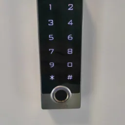 Panel dotykowy kontroli dostępu z czytnikiem linii papilarnych i klawiaturą numeryczną, zamontowany na białej ścianie.