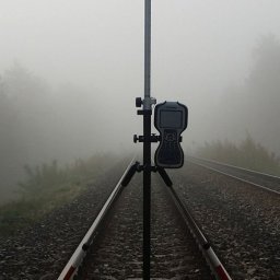 Usługi Geodezyjne GEOAR-2 - Geodezyjny odbiornik GPS ustawiony na trójnogu, pomiar na torach kolejowych we mgle.