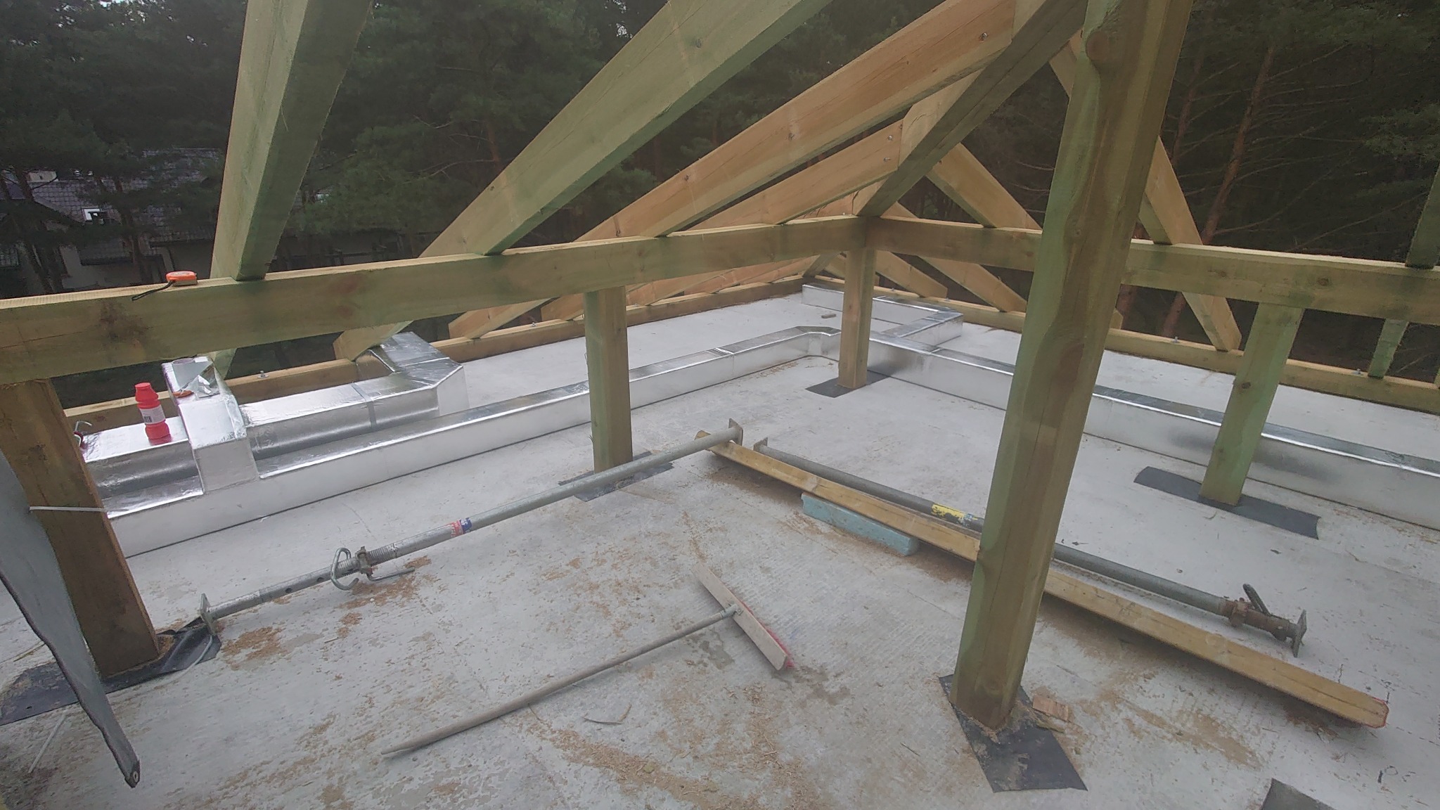 Montaż izolowanych kanałów wentylacyjnych w przestrzeni poddasza z drewnianą konstrukcją więźby dachowej i elementami wsporczymi