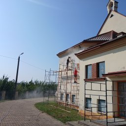Nazar hulenchin - Dwóch pracowników na rusztowaniu czyści elewację budynku sakralnego pod wysokim ciśnieniem, przygotowując ją do dalszych prac.
