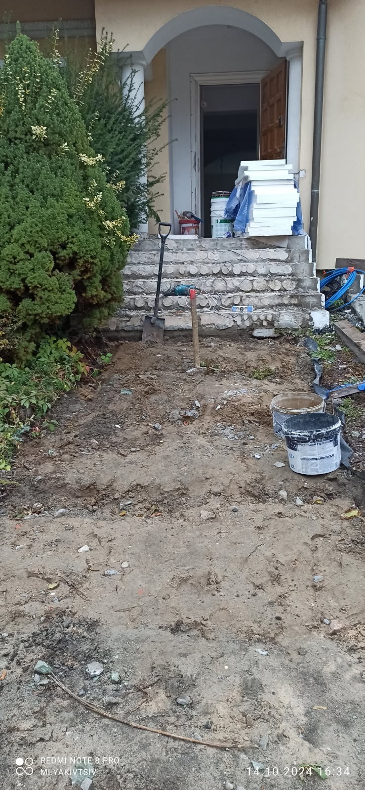 Przygotowanie terenu przed wejściem do domu, widoczne narzędzia, wiaderka z farbą, oraz styropian na schodach.