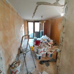 Roman Korolchuk - Pokój w trakcie remontu: zerwana płyta gipsowa na suficie, ściany z resztkami farby, drabina, wiaderka z farbą i gruzem, przygotowanie do dalszych prac. Stan 'Przed'.