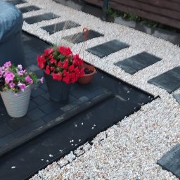 Mkb-Bruk - Aranżacja przestrzeni przydomowej z ścieżką z prostokątnych płyt i białego grysu, obok jacuzzi i donic z kwiatami.