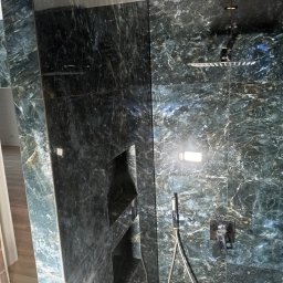 Pro-Efekt Przemysław Zimoch - Luksusowy prysznic typu walk-in z ciemnozielonymi, marmurkowymi płytkami, wbudowanymi półkami i deszczownicą. Nowoczesny design z eleganckimi detalami.
