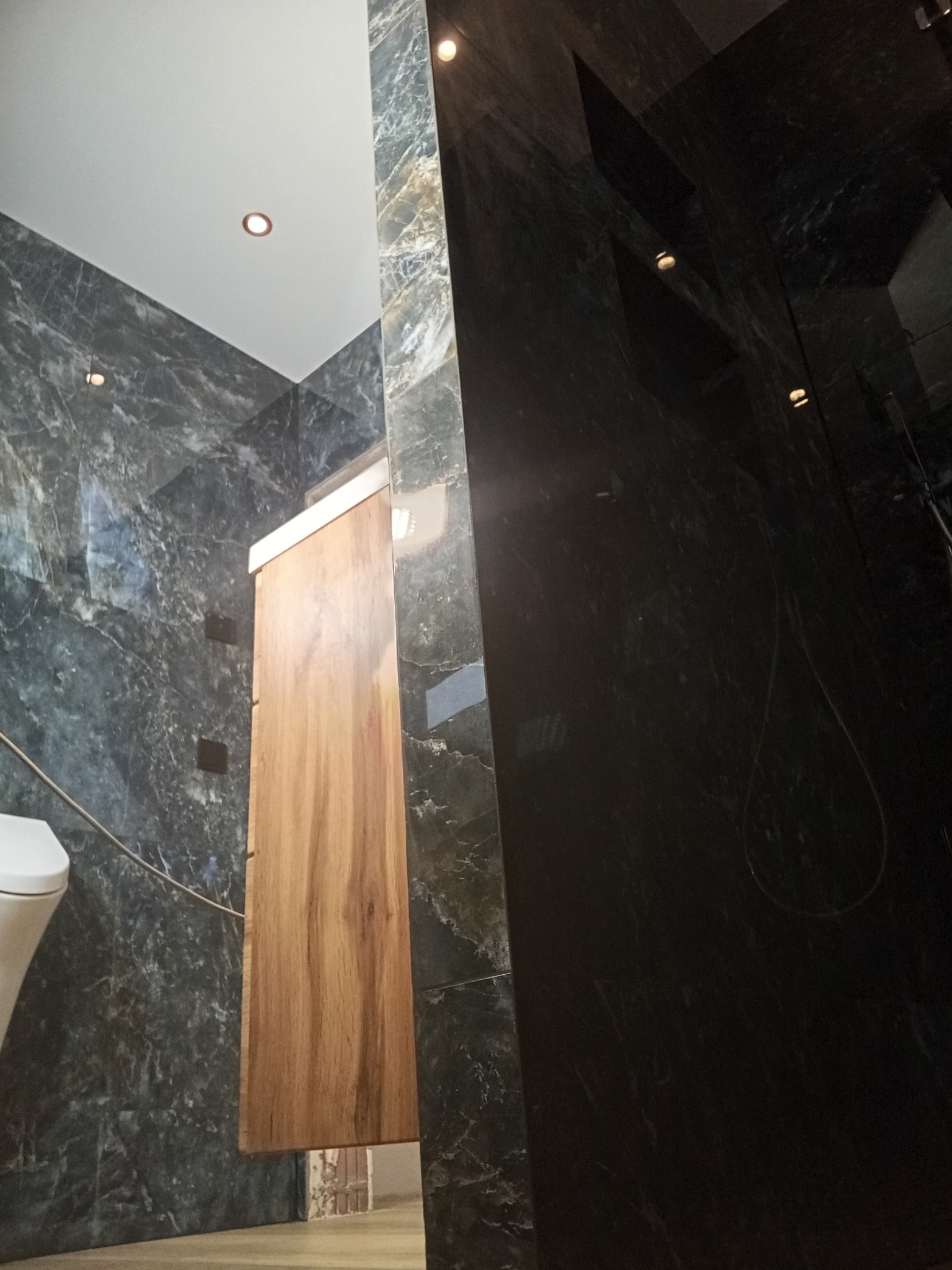 Nowoczesna łazienka w Kniatowach z marmurowymi płytkami i drewnianą szafką pod umywalkę. Minimalistyczny design i oświetlenie punktowe.