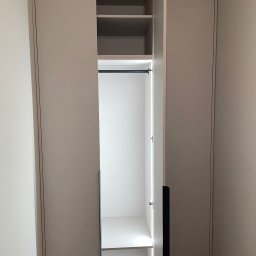 ERNEST STANIK - Jasna szafa wnękowa z otwartymi drzwiami, widoczne półki i drążek na ubrania, oświetlenie LED wewnątrz. Minimalistyczny design, gładkie fronty.