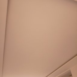 Artur Zaborowski - Gładka, beżowa powierzchnia sufitu podwieszanego z delikatnym oświetleniem LED wzdłuż krawędzi, widok z dołu.