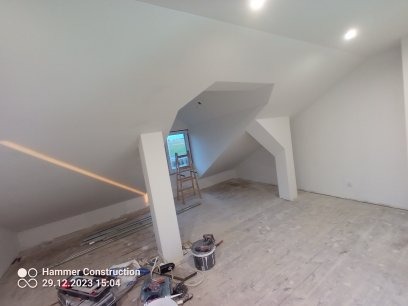 Poddasze po nałożeniu gładzi szpachlowej, przygotowane do malowania, widoczne narzędzia i drabina przy oknie.