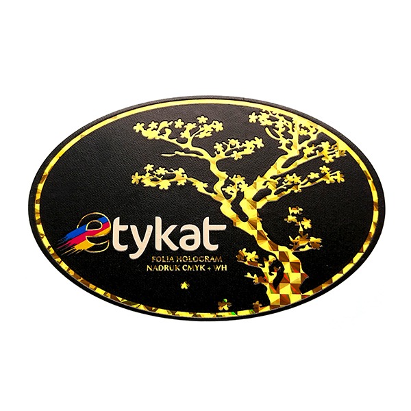 Owalna naklejka z czarnym tłem i złotym obramowaniem, przedstawiająca stylizowane drzewo bonsai w kolorze złotym oraz napis 'etykat' z efektem holograficznym i informacją 'FOLIA HOLOGRAM, NADRUK...