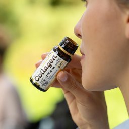 Fotografia i wideografia reklamowa Szymon Kryszczak - Kobieta pije shot kolagenowy z małej butelki, widoczny profil twarzy i etykieta produktu z QR kodem.