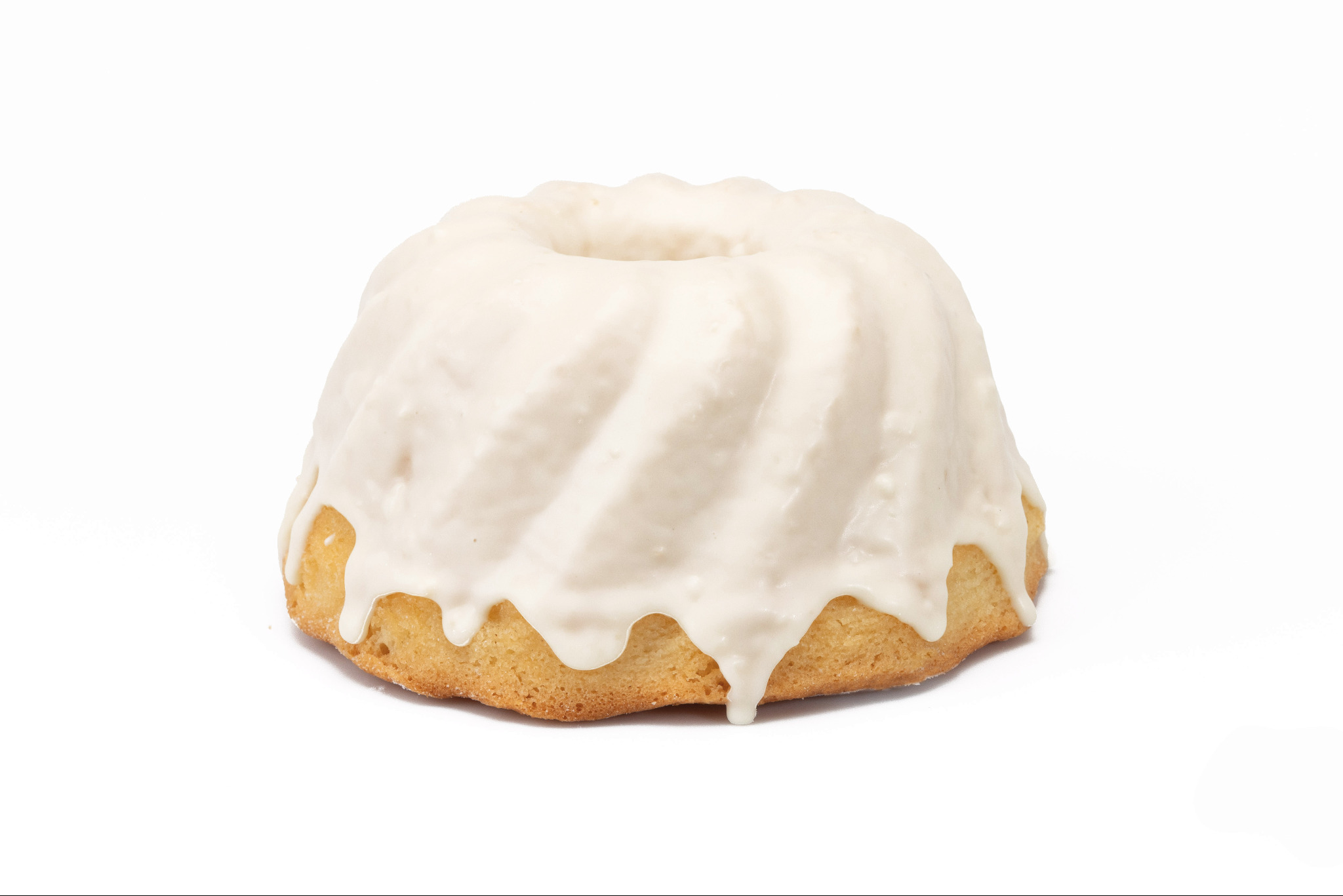 Babka piaskowa z lukrem w kształcie wieży, sfotografowana na białym tle. Lukier spływa po bokach, tworząc efektowne zacieki. Delikatne oświetlenie podkreśla teksturę ciasta.