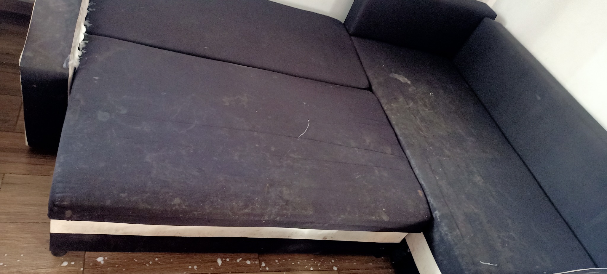 Brudna, ciemna kanapa narożna przed czyszczeniem tapicerki w Jarotach, widoczne plamy i zabrudzenia na materiale.