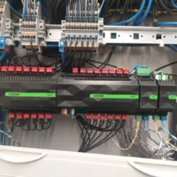 Rozdzielnica elektryczna z modułami Loxone Relay i DI Tree, liczne przewody podłączone do listew zaciskowych, widoczne elementy montażowe na szynie DIN.