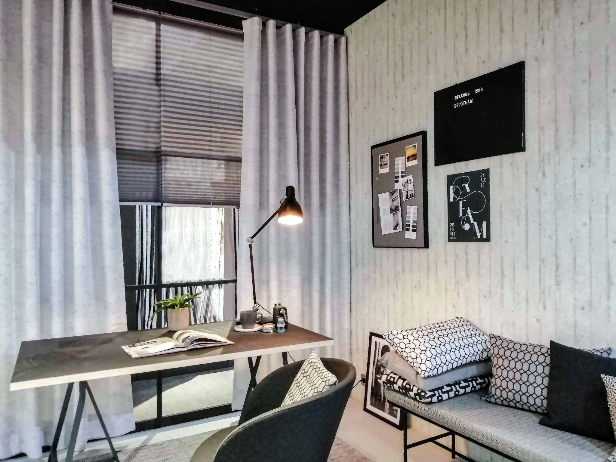 Jasne, marszczone zasłony przy oknie z żaluzjami, biurko z lampką i otwartą książką, dekoracyjne poduszki na ławce, szara ściana z tablicami.