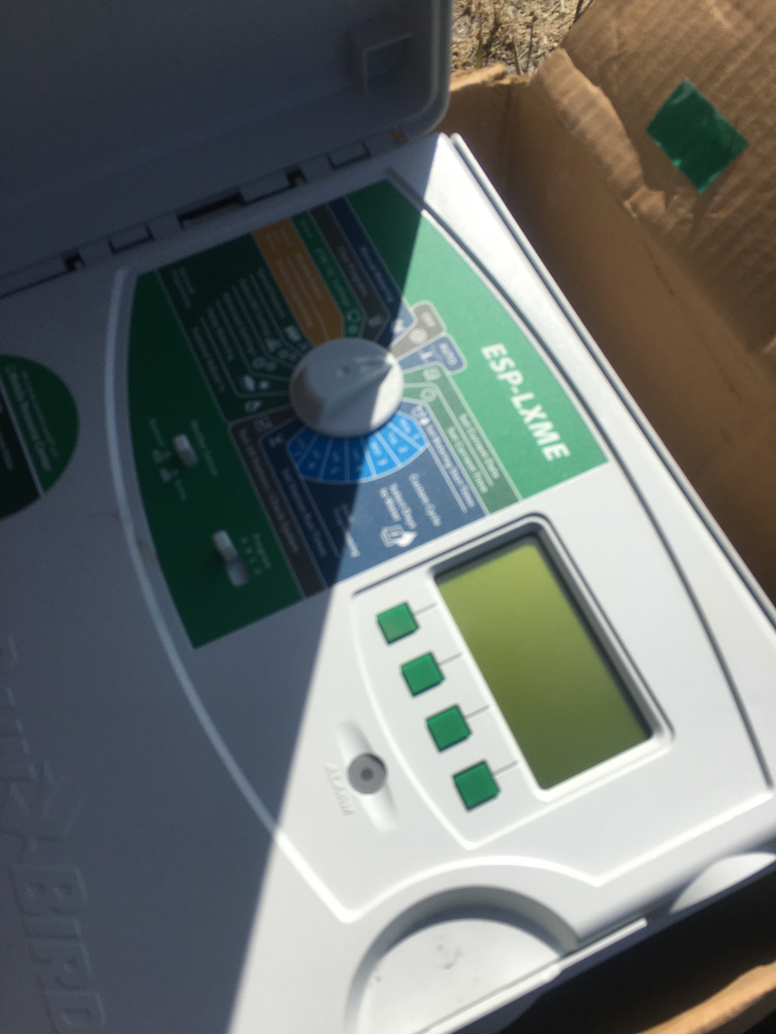 Kontroler nawadniania Rain Bird ESP-LXME w kartonowym pudełku, widoczny panel sterowania z pokrętłem i ekranem.