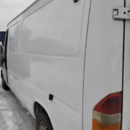 Biały samochód dostawczy z otwartymi drzwiami, widoczne ślady użytkowania i zabrudzenia na karoserii