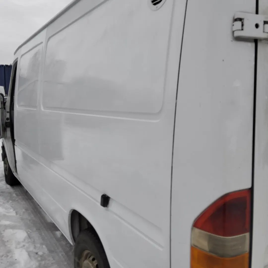 Biały samochód dostawczy, widok z boku, z otwartymi tylnymi drzwiami, na tle szarego nieba.