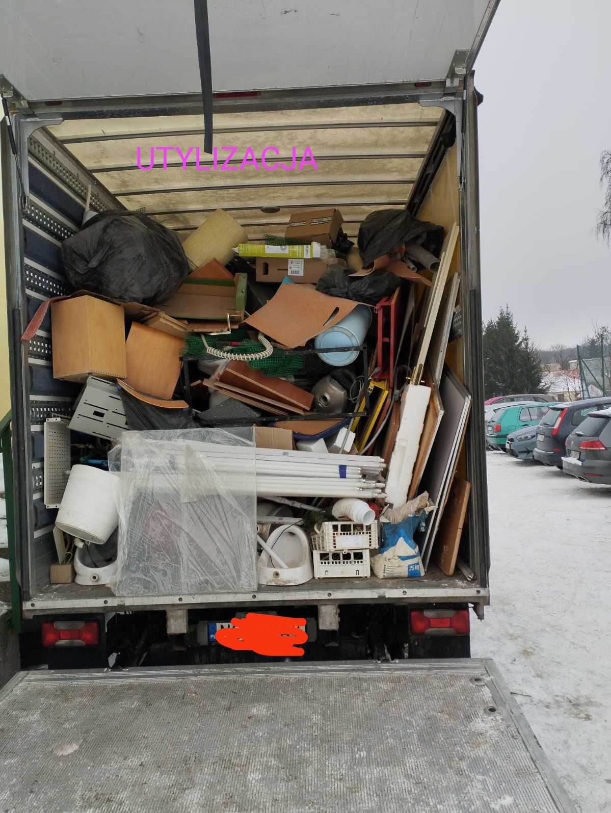 Wnętrze wypełnionej po brzegi skrzyni ładunkowej pojazdu dostawczego, zawierającej różnorodne przedmioty przeznaczone do utylizacji, w tym elementy wyposażenia łazienki, meble, opakowania i inne...