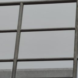 Mateusz Mazurek - Fragment metalowej konstrukcji schodów zewnętrznych z kwadratową, poziomą barierką i żółtą naklejką informującą o dopuszczalnym obciążeniu.