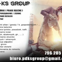 Pracownik w kasku i masce ochronnej używa młota pneumatycznego do rozbiórki ściany, widoczne gruzy i fragment ściany z cegieł.