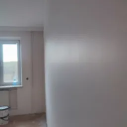 Świeżo pomalowana ściana w pokoju, widoczny fragment okna i wiadro farby na podłodze, delikatna faktura farby odbija światło.