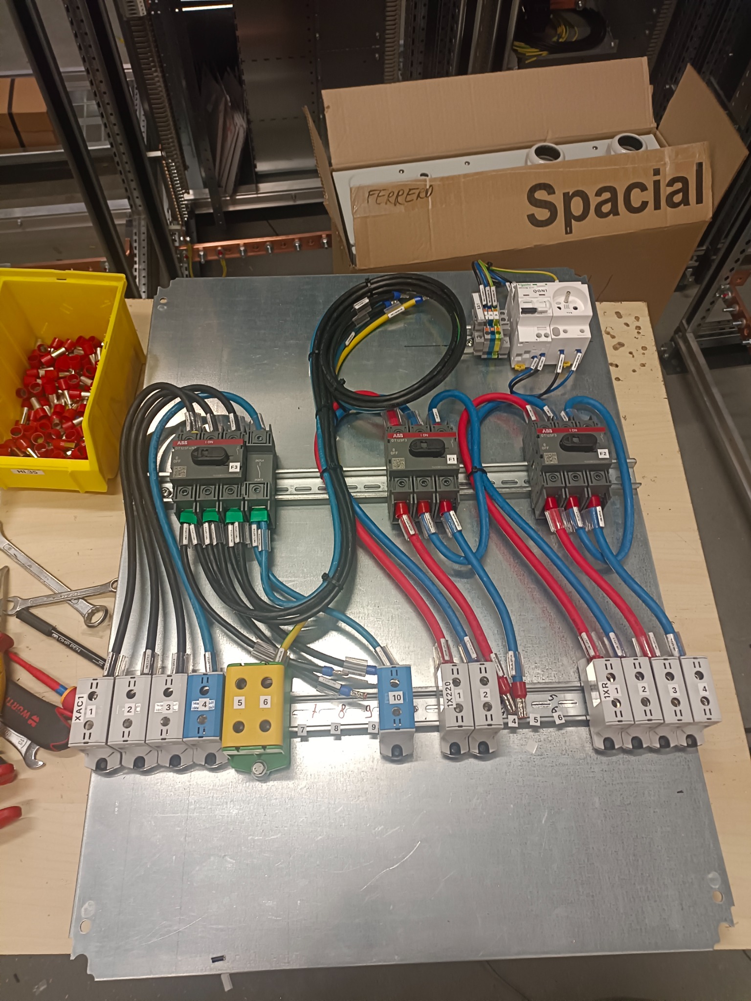 Przygotowywany panel elektryczny w Wieliczce z zamontowanymi stycznikami, zabezpieczeniami i listwami zaciskowymi, okablowany przewodami w kolorach niebieskim, czerwonym i czarnym, z widocznymi...