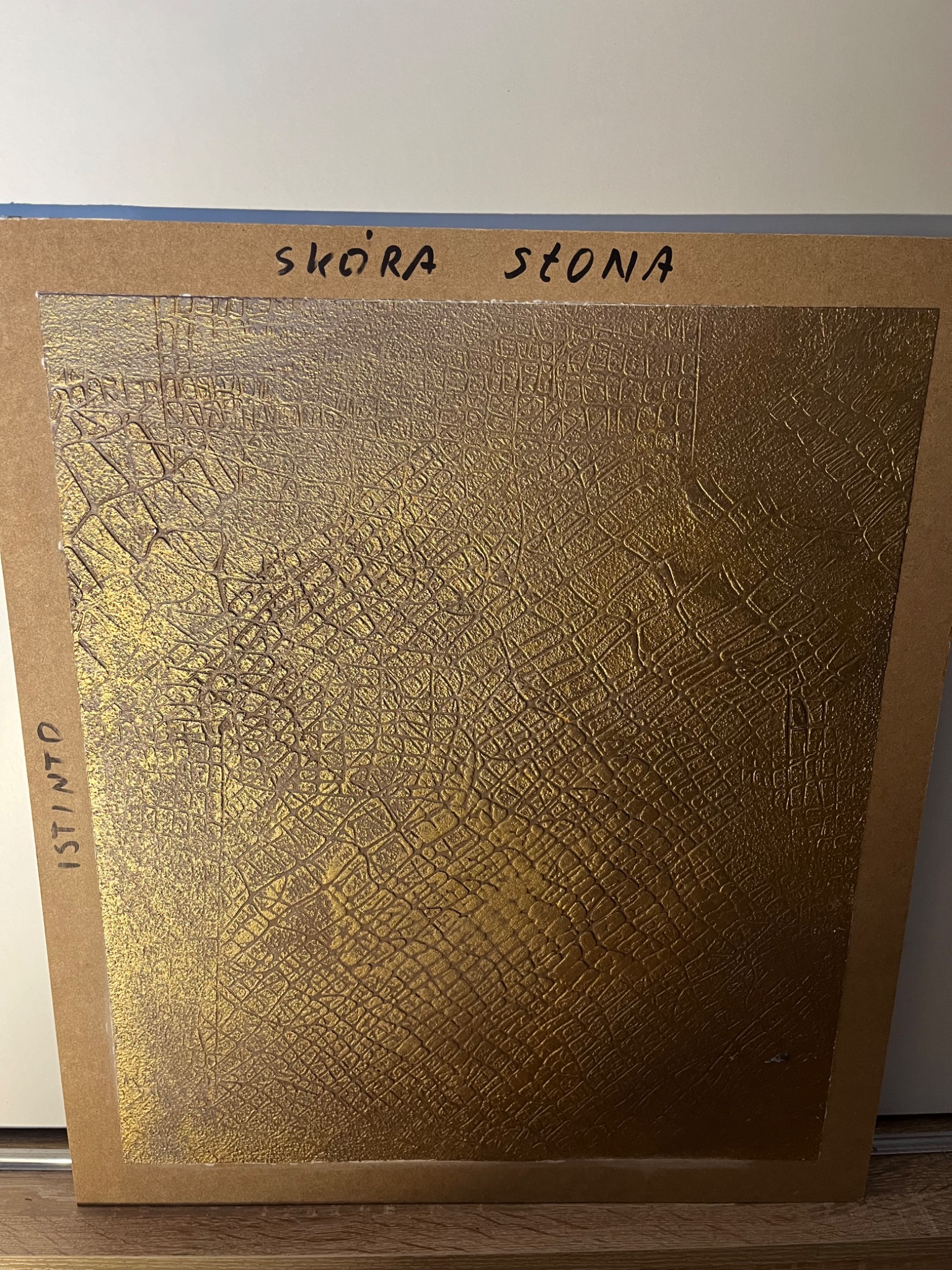 Próbka dekoracyjnej faktury ściany w odcieniach złota, imitująca skórę słonia, umieszczona na kartonowej planszy z napisem 'SKÓRA SŁONA' i 'ISTINTO' z boku.