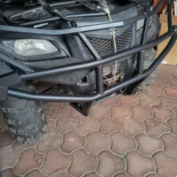 Czarny quad z metalowym orurowaniem ochronnym w Nowym Tomyślu. Solidna konstrukcja zabezpiecza przód pojazdu, widoczne detale spawów i opon terenowych.