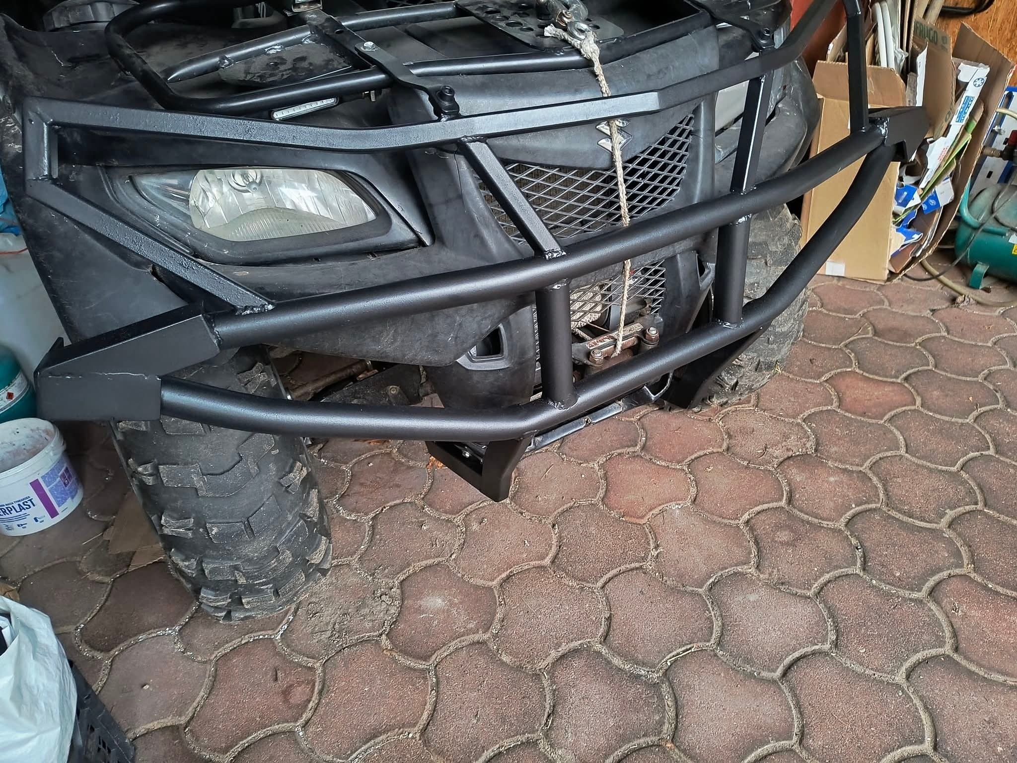 Czarny quad z metalowym orurowaniem ochronnym w Nowym Tomyślu. Solidna konstrukcja zabezpiecza przód pojazdu, widoczne detale spawów i opon terenowych.