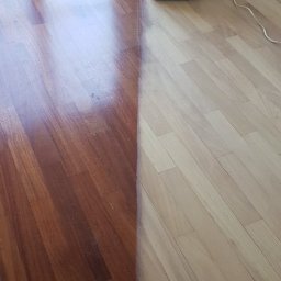 Kamil Maliszewski - Parkiet w trakcie renowacji: po lewej stronie wycyklinowany i polakierowany, po prawej surowe drewno, obok maszyna do cyklinowania z workiem na pył.