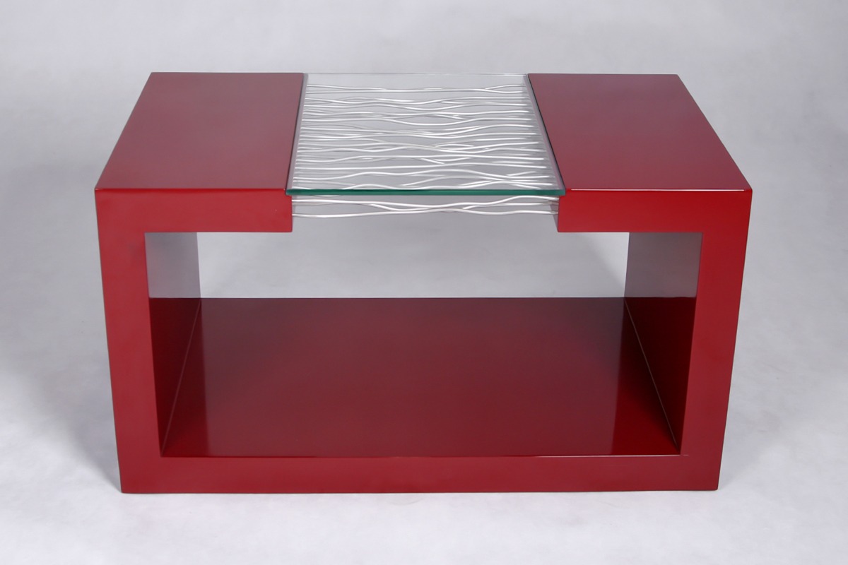 Nowoczesny stolik kawowy w kolorze wiśniowym z blatem z przezroczystego szkła z dekoracyjnymi, srebrnymi falami.