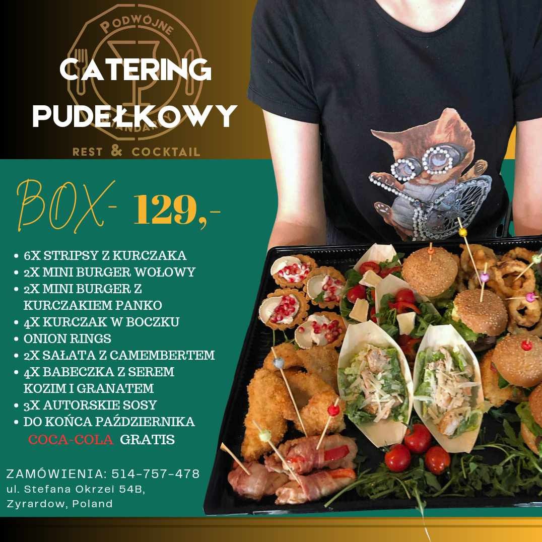 Osoba w czarnej koszulce z nadrukiem kota trzyma czarną tacę z różnorodnymi przekąskami: mini burgery, stripsy z kurczaka, sałatki w łódeczkach, babeczki z serem kozim i granatem, krążki cebulowe...