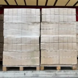 Dwie palety brykietu drzewnego, zabezpieczone folią stretch, załadowane wewnątrz naczepy ciężarówki.