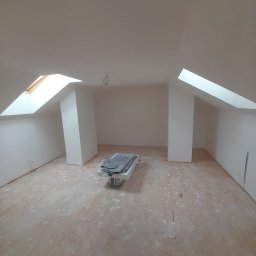 Jakub Zmuda - Pokój na poddaszu z oknami dachowymi w trakcie prac wykończeniowych, podłoga zabezpieczona folią, widoczny sprzęt malarski przykryty folią.
