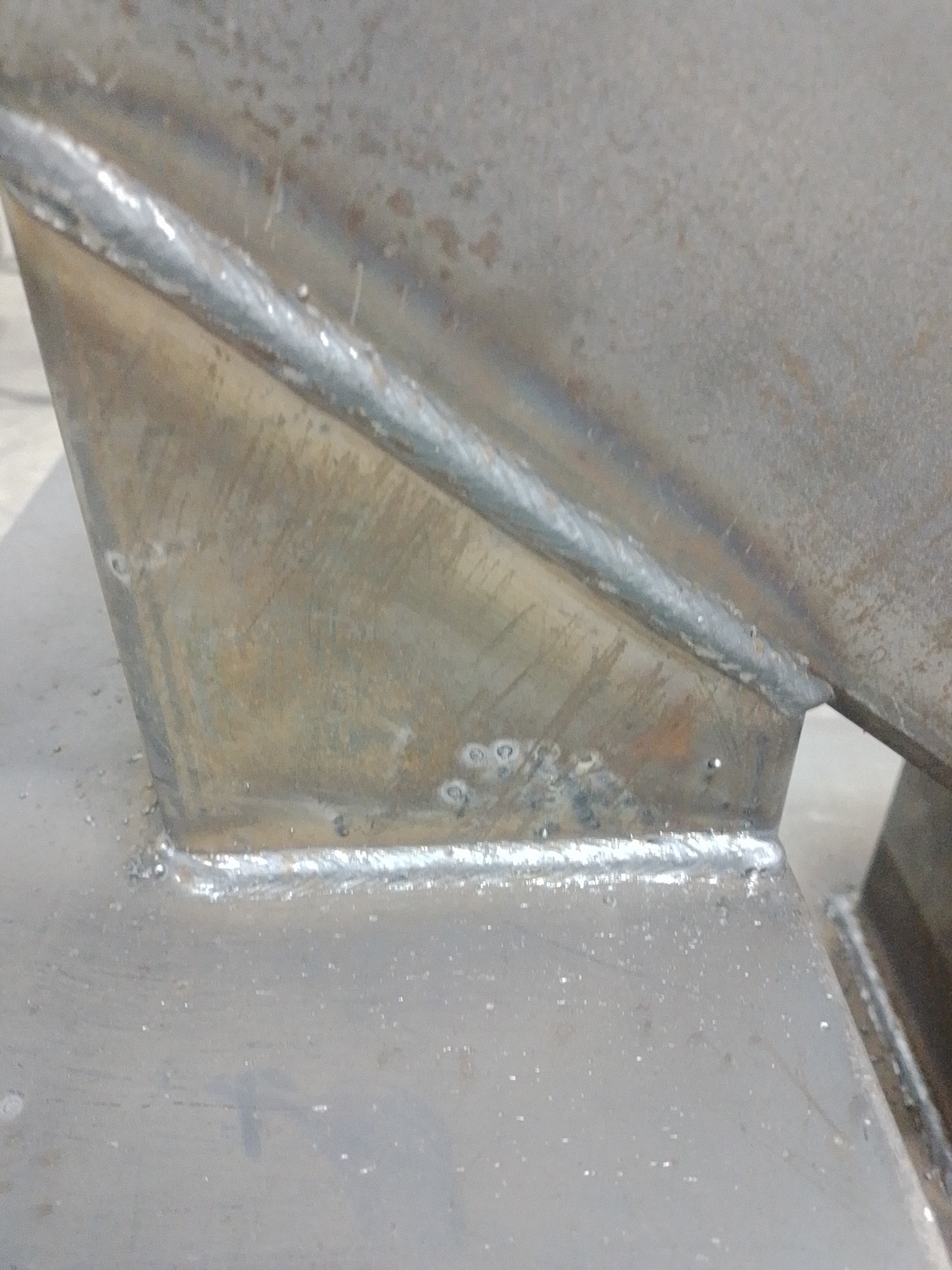 Spoina łącząca elementy konstrukcji stalowej, widoczne ślady po spawaniu i niedoskonałości powierzchni metalu.