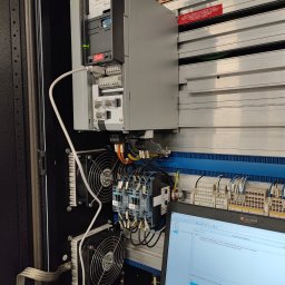 OMIautomatyka - Szafa sterownicza z zamontowanym falownikiem Danfoss, podłączonym do laptopa z uruchomionym oprogramowaniem diagnostycznym, widoczne moduły Siemens i wentylatory chłodzące.