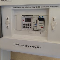 OMIautomatyka - Otwarta skrzynka rozdzielcza domofonowa RD1 z widocznym przekaźnikiem czasowym, zasilaczem 230V/12VDC oraz wyłącznikiem nadprądowym marki Eaton.