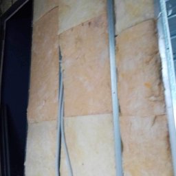 ROBERT MYKYTA RMD - Ściana w trakcie izolacji: wełna mineralna pomiędzy metalowymi profilami, widoczne przewody elektryczne w peszlu.