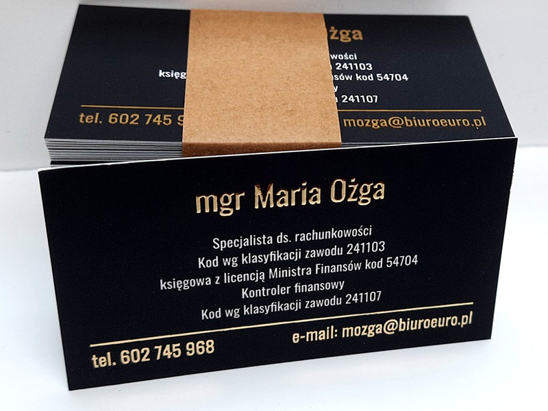 Stos wizytówek z czarnym tłem i złotym tekstem, owinięty brązowym papierem, prezentujący dane kontaktowe mgr Marii Ożgi, specjalisty ds. rachunkowości z Bytomia.