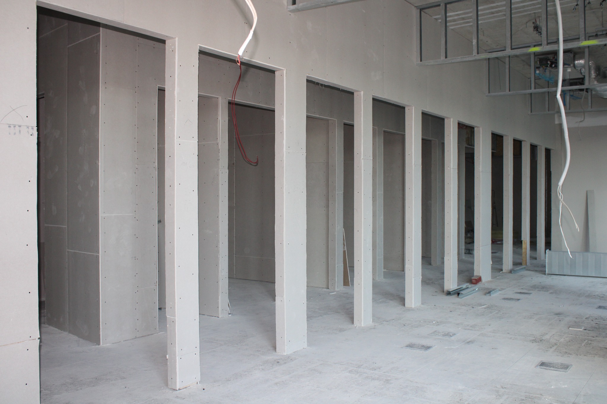 Wnętrze biurowe w trakcie montażu ścian działowych z płyt karton-gips, widoczne profile i instalacje pod sufitem.