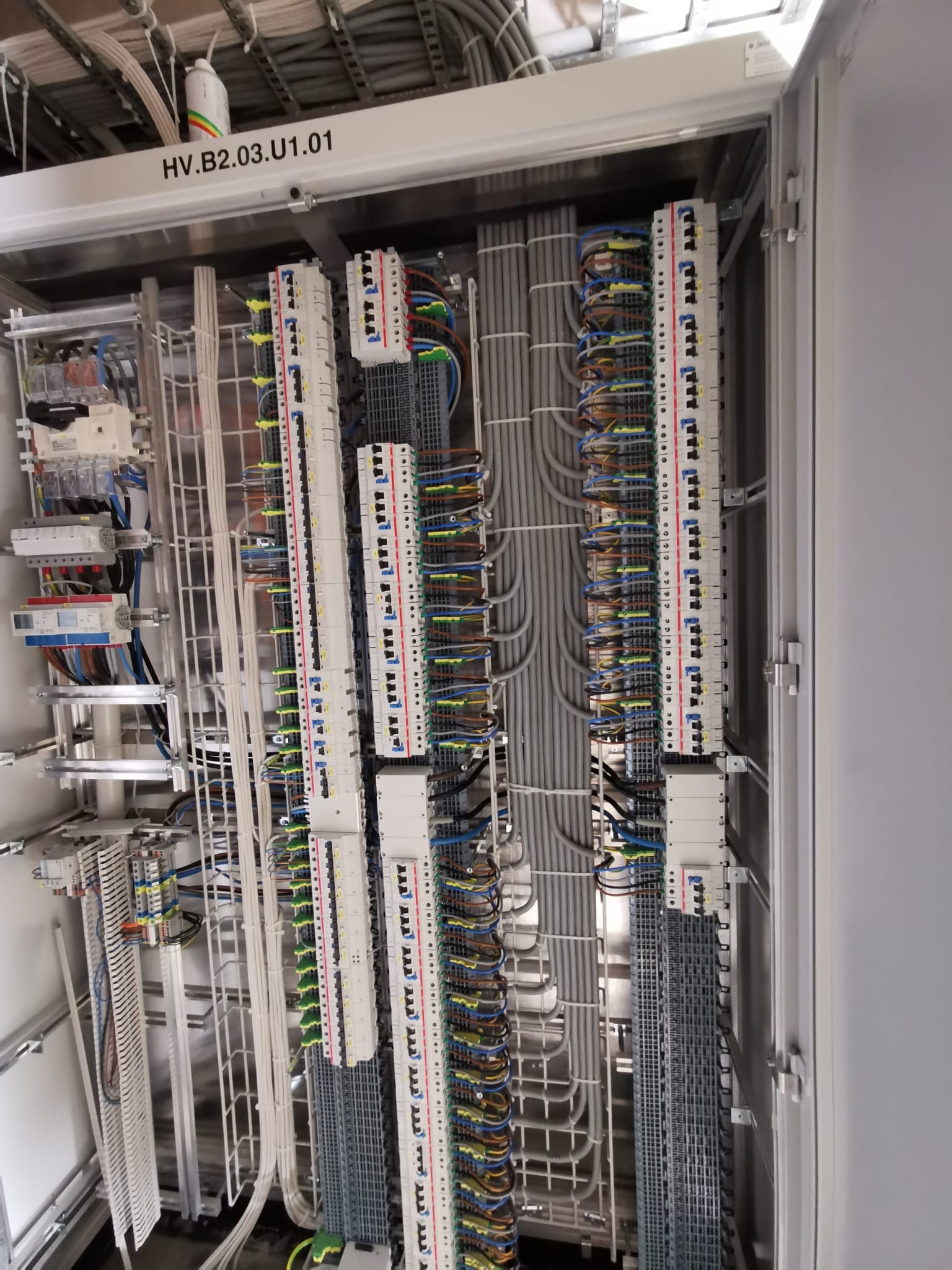 Wnętrze szafy sterowniczej z precyzyjnie ułożonymi przewodami i listwami zaciskowymi, widoczne oznaczenia HV.B2.03.U1.01 na górnej belce