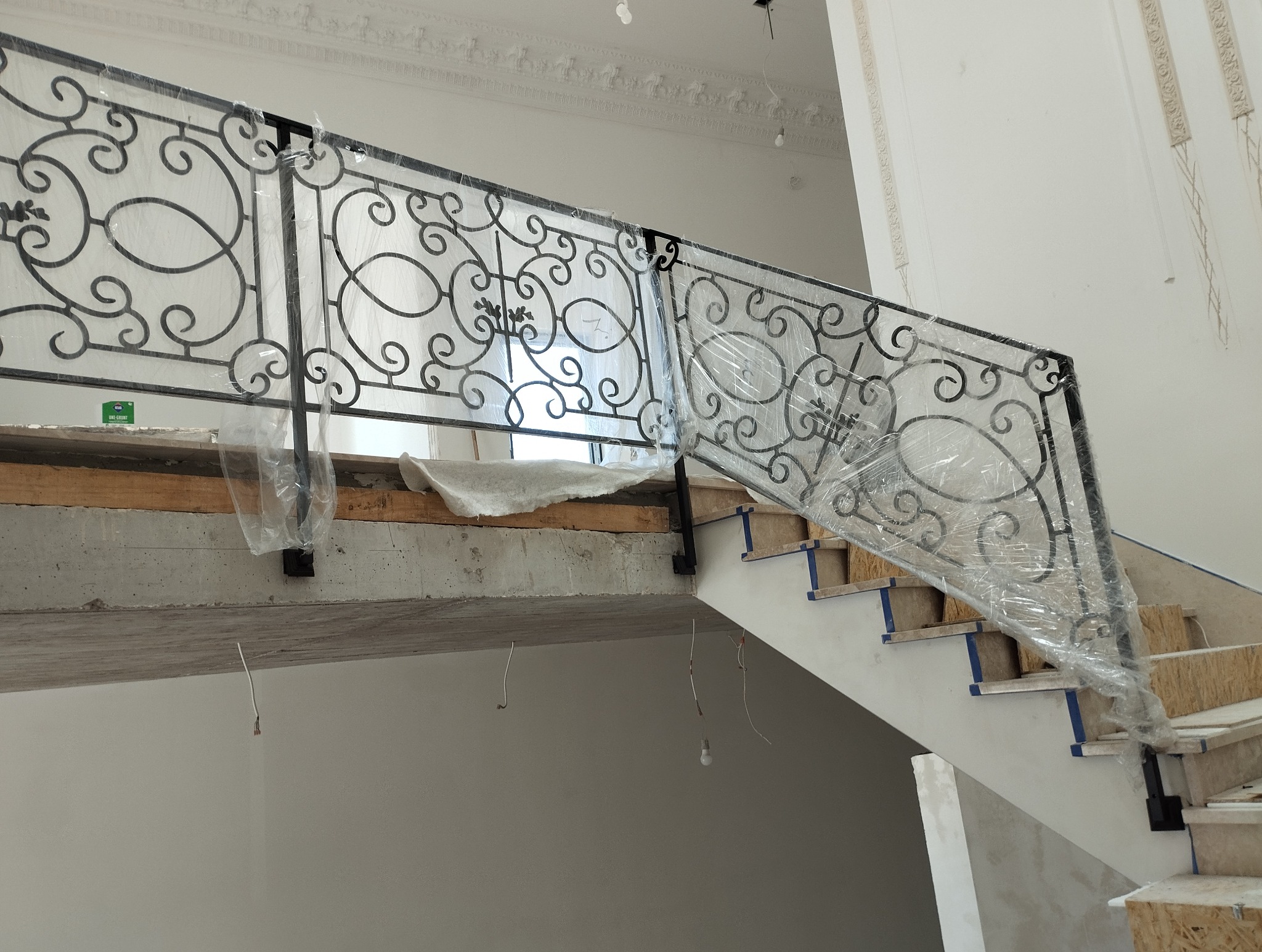 Kute balustrady schodowe w folii ochronnej podczas montażu w Parczewie. Elementy dekoracyjne z motywem roślinnym. Wykończenie w kolorze czarnym.