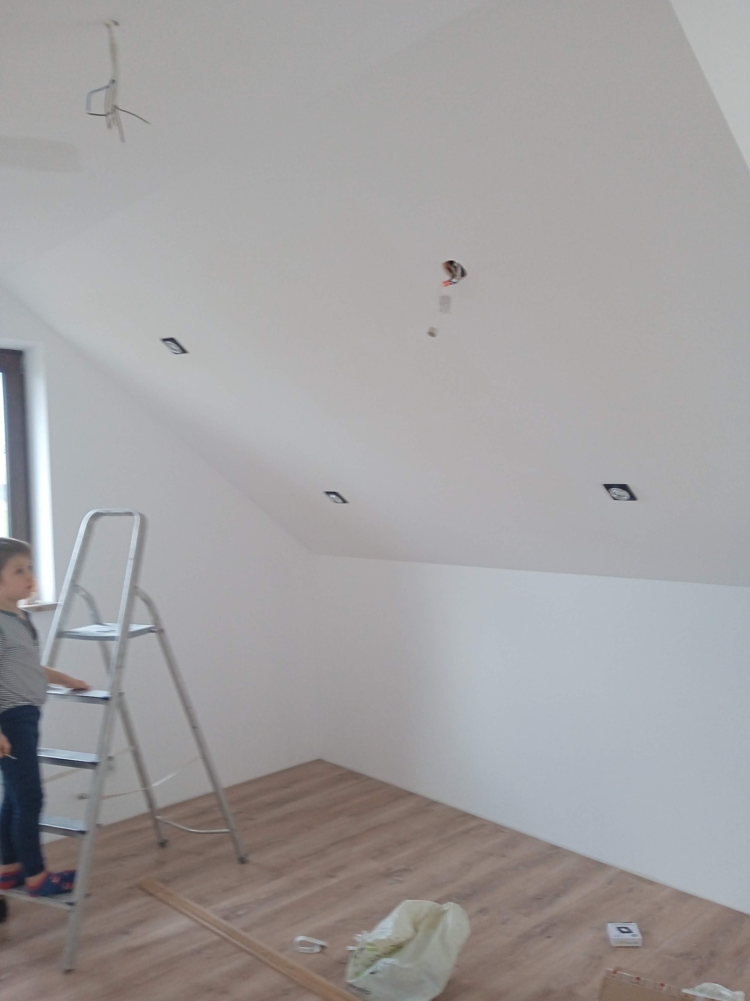 Poddasze po malowaniu w Wielgus. Widoczne halogeny w suficie, drabina i fragment podłogi. W tle okno.