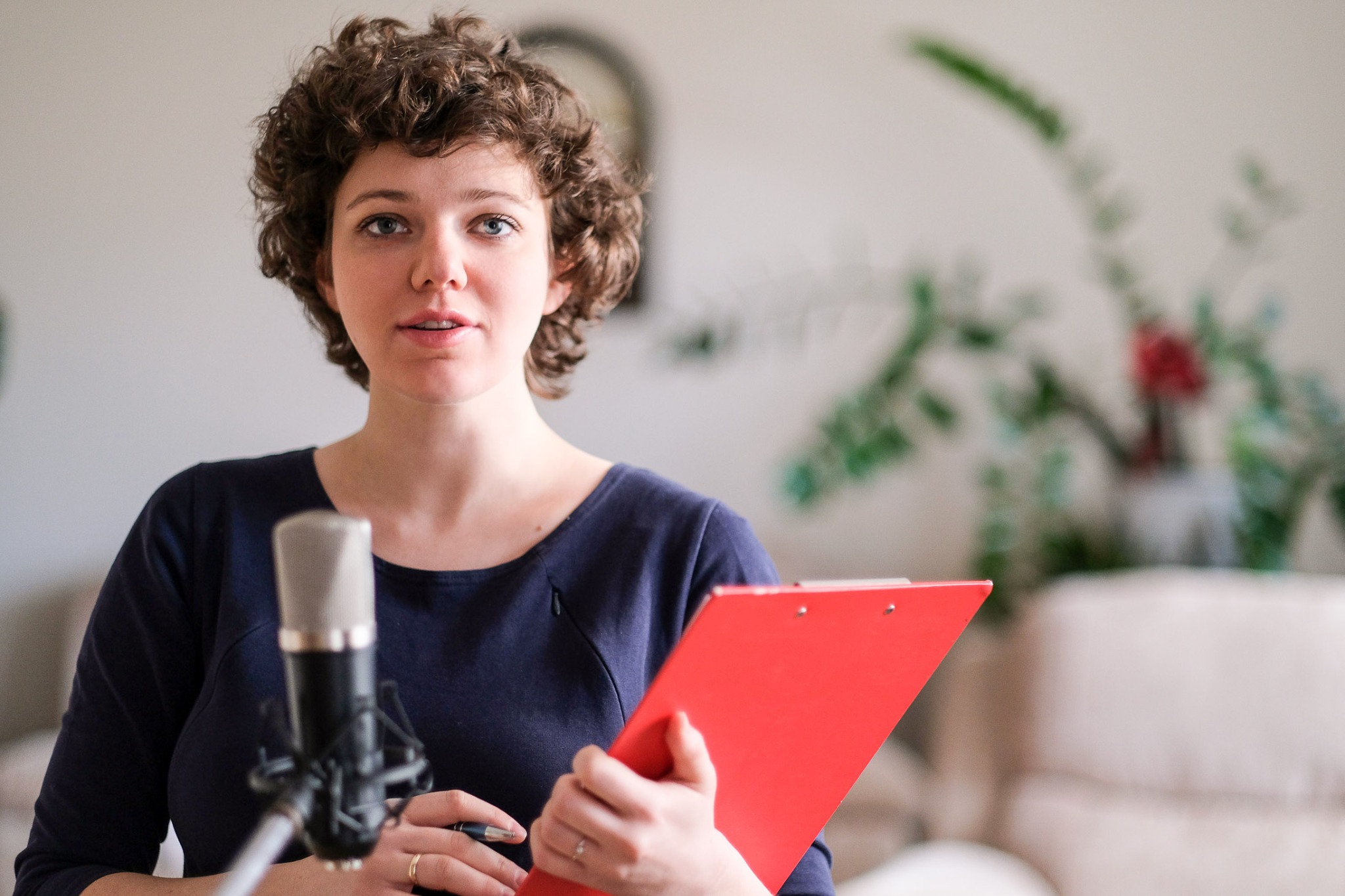 Kobieta z mikrofonem i czerwoną podkładką, prawdopodobnie nagrywająca tłumaczenie lub dyktująca tekst.