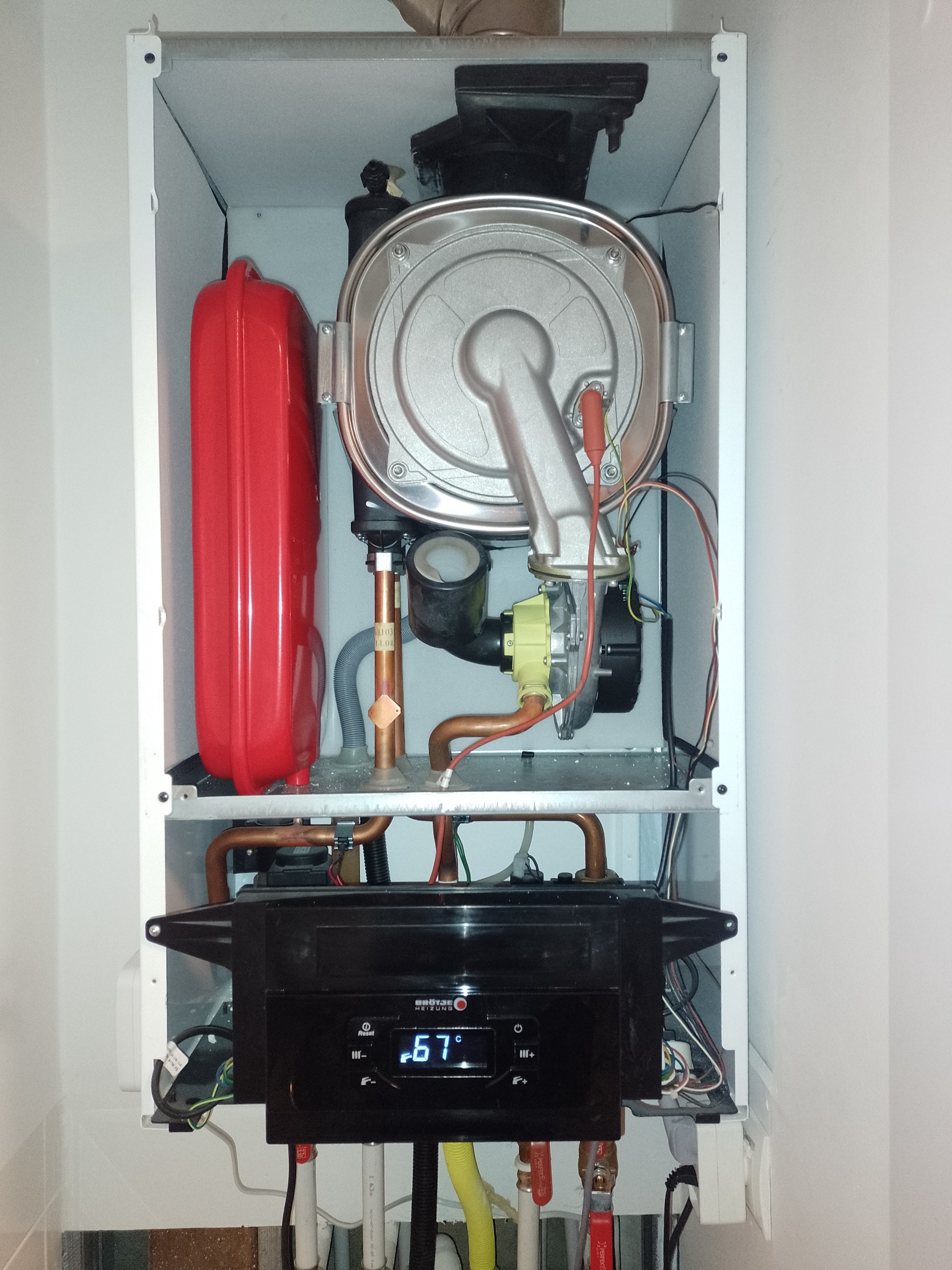 Wnętrze szafki z zamontowanym piecem gazowym w mieszkaniu w Warszawie, widoczne elementy instalacji, rury miedziane i panel sterowania.