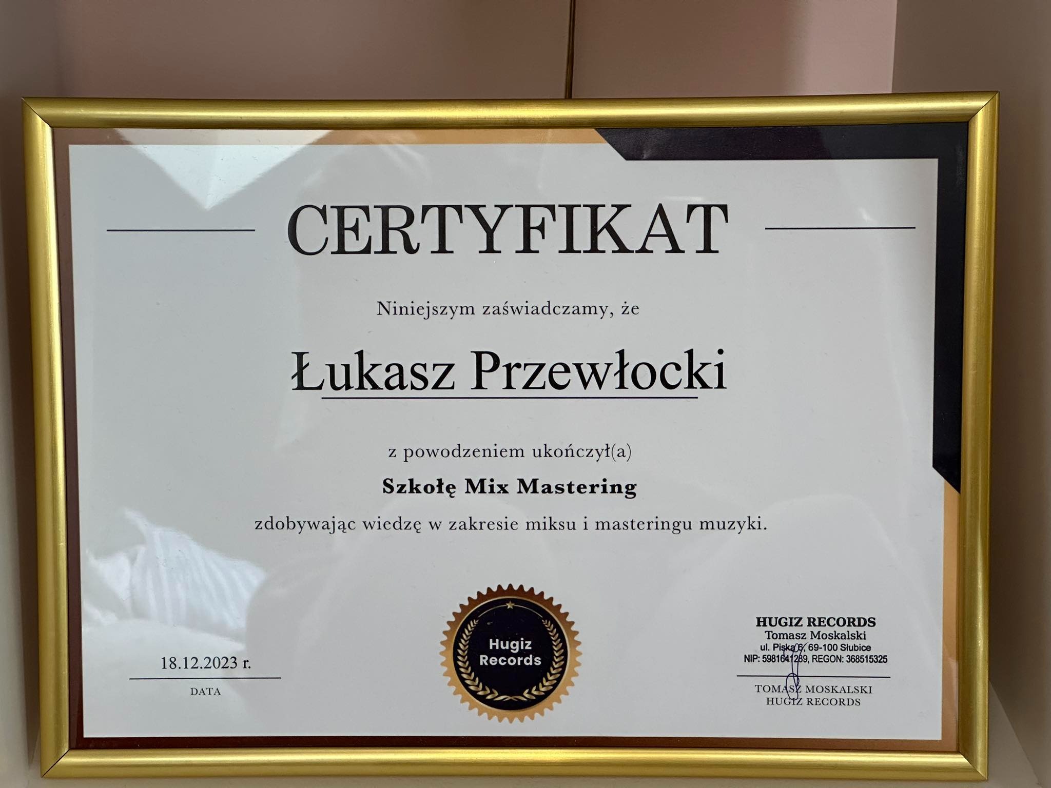 Certyfikat ukończenia Szkoły Mix Masteringu przez Łukasza Przewłockiego, wydany przez Hugiz Records, oprawiony w złotą ramkę, z datą 18.12.2023.